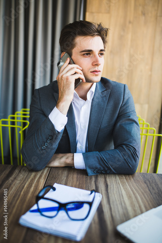 Young businessman caucasian in his office on phone in front notebook photo