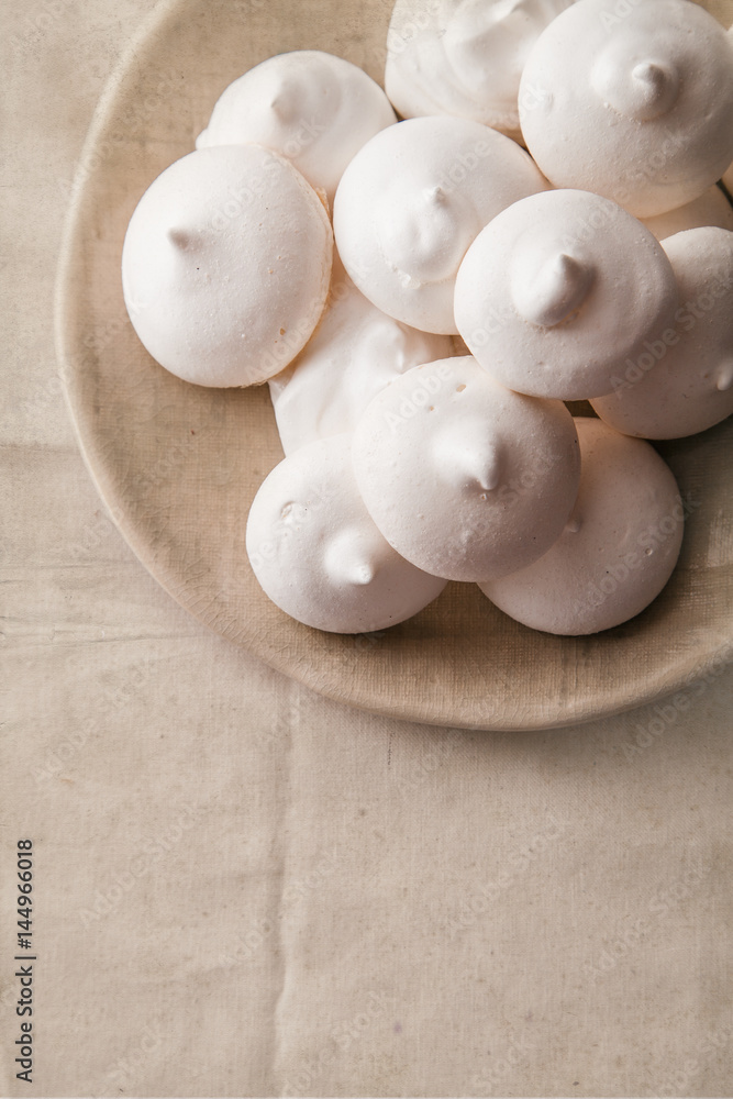 Homemade meringues on ceramic plate and linen fabric Homemade meringues on ceramic plate and linen fabric