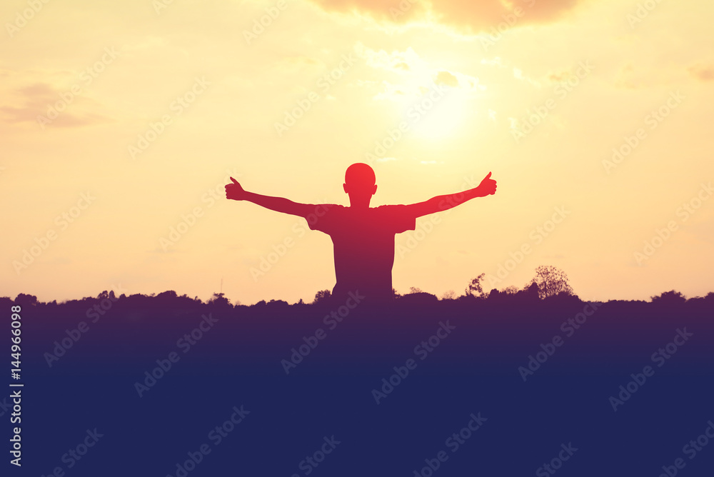 Silhouette of man extend the arms with sunset background