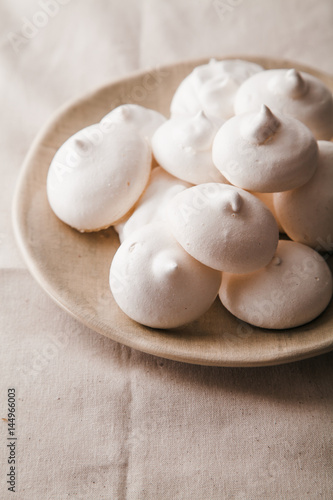 Homemade meringues on ceramic plate and linen fabric