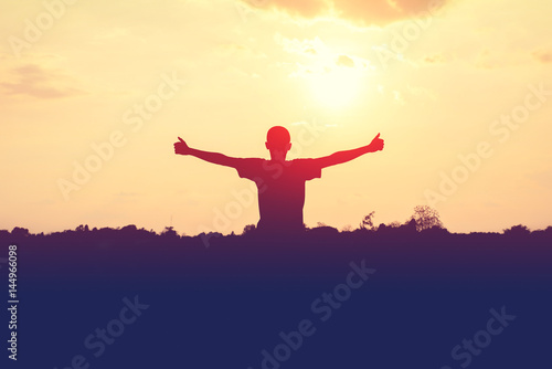 Silhouette of man extend the arms with sunset background