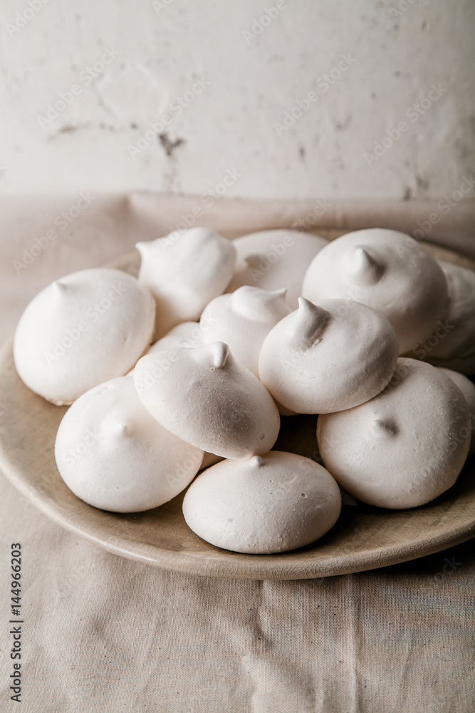 Homemade meringues on ceramic plate and linen fabric Homemade meringues on ceramic plate and linen fabric