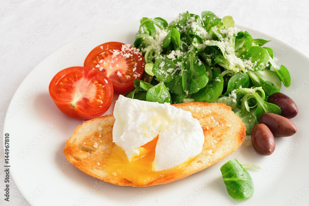 breakfast set of pan fried toast with poached egg, cut tomato, kalamata olives, and green salad dressed with olive oil and lemon juice and sprinkled with grated cheese breakfast set of pan fried toast with poached egg, cut tomato, kalamata olives, and green salad dressed with olive oil and lemon juice and sprinkled with grated cheese