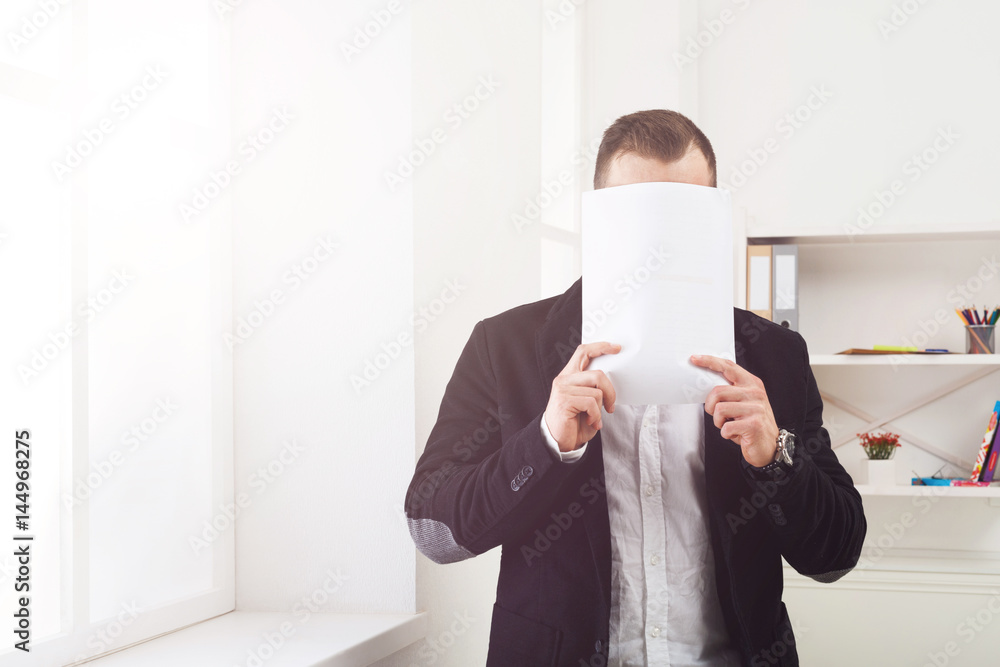 Businessman covering face with blank paper