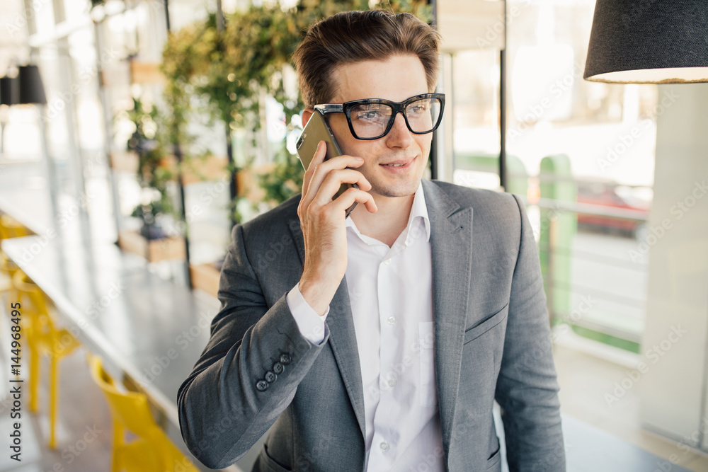 Smiling businessman sitting and using mobile phone in office Smiling businessman sitting and using mobile phone in office