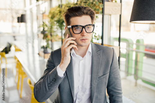Smiling businessman sitting and using mobile phone in office photo