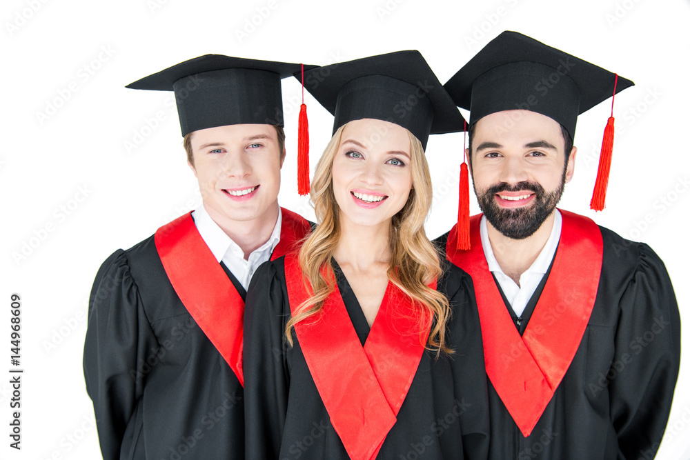 Happy students in mortarboards and mantles smiling at camera Happy students in mortarboards and mantles smiling at camera