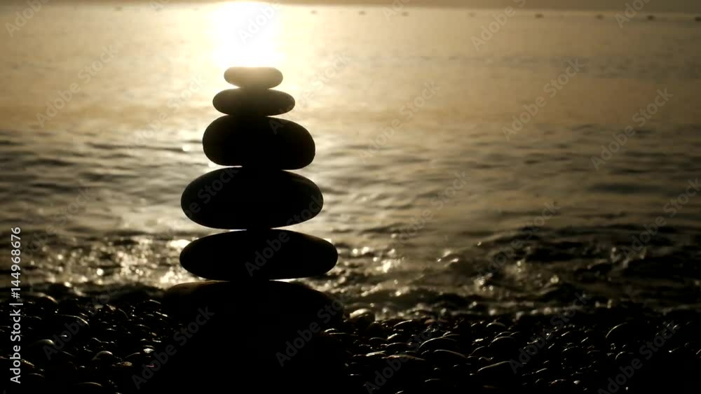 Closeup of pyramid of sea stones on seashore at golden sunset time. Beautiful nature landscape. Real time video footage. Closeup of pyramid of sea stones on seashore at golden sunset time. Beautiful nature landscape. Real time video footage.