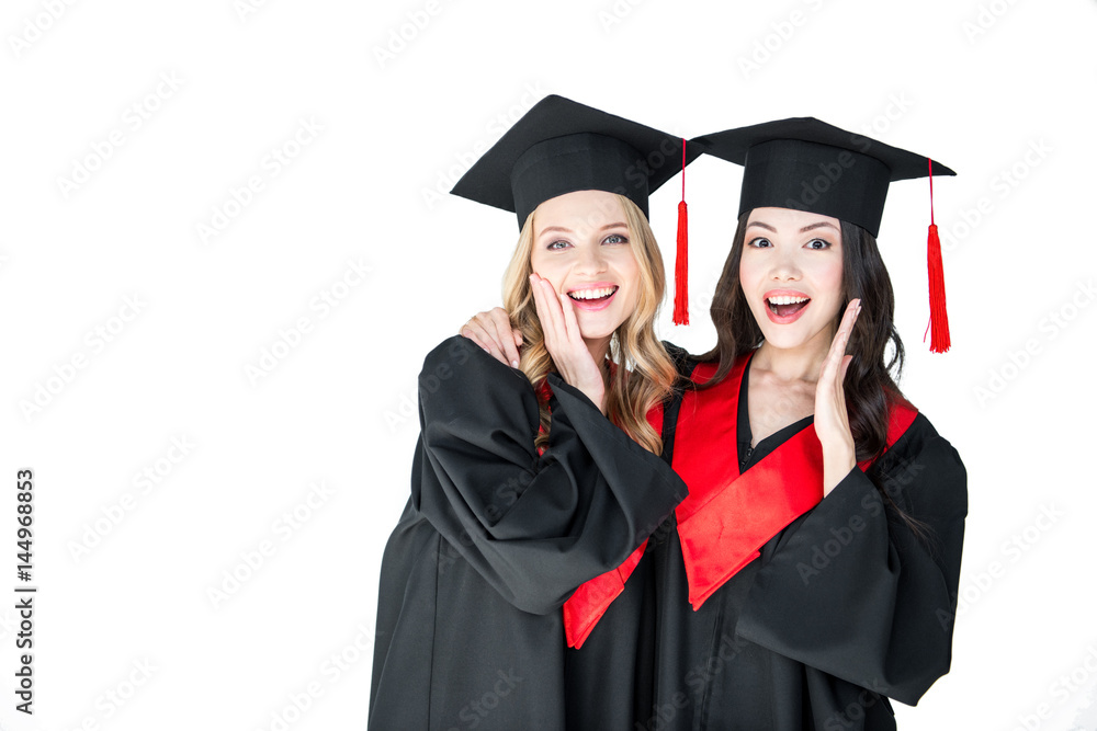 attractive excited students in graduation caps hugging isolated on white attractive excited students in graduation caps hugging isolated on white