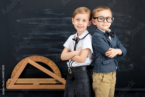 Little girl and boy against blackboard. School concept