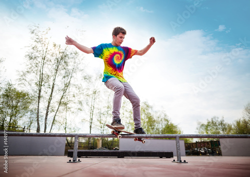Skater doing smith grind on rail in skatepark