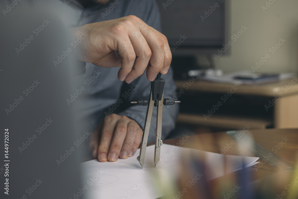 Close-up of man using compasses at desk Close-up of man using compasses at desk