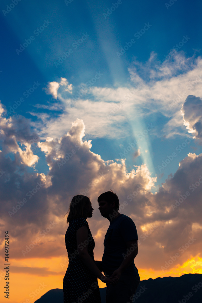 Silhouette of a newly-married couple on the background of the setting sun in Perast in Montenegro.