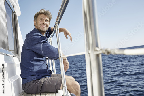 Portrait of content mature man sitting on his motor yacht