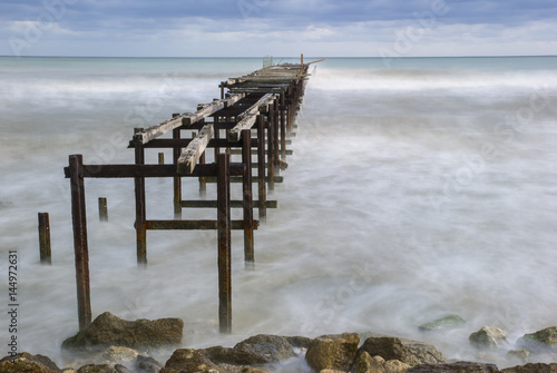 Deserted pier on the Bulgarian Black Sea shore under an agitated water and approaching storm photo