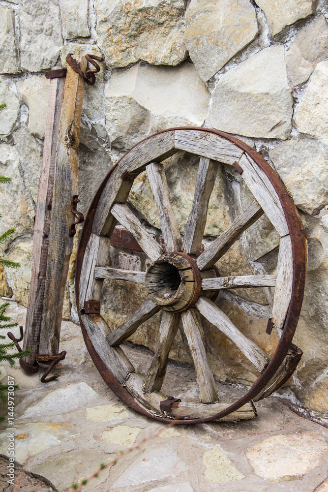 Old wooden and metall wheel on stone wall