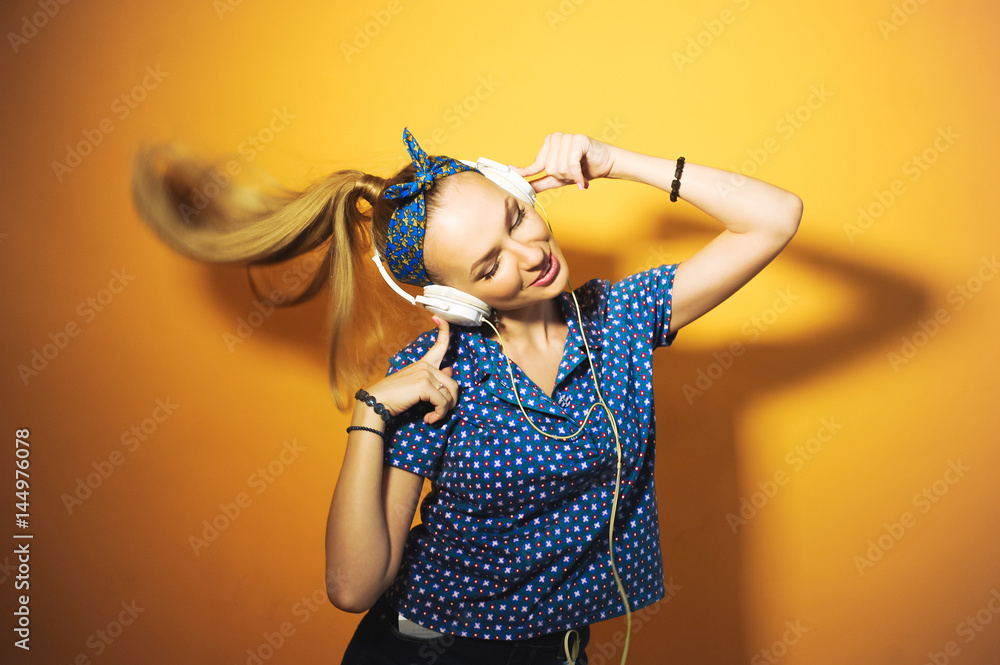 close-up portrait of a girl on a yellow background in studio beautiful young bright sexy hair in a ponytail, wearing headphones listening to music and singing and posing with red lips and manicure