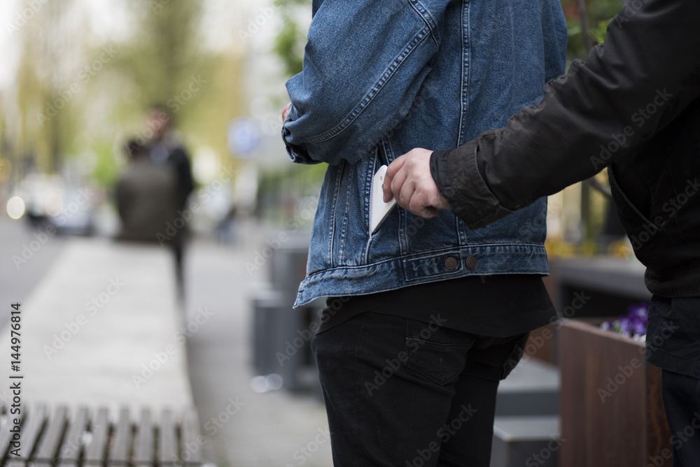 Dieb stiehlt smartphone aus einer Tasche StockFoto Adobe Stock