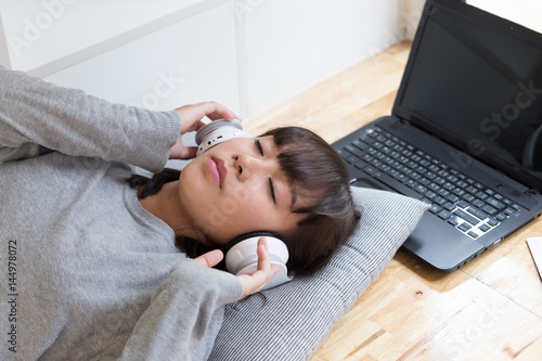 asian girl female teenager student lying and listening to music from headphone - lifestyle concept