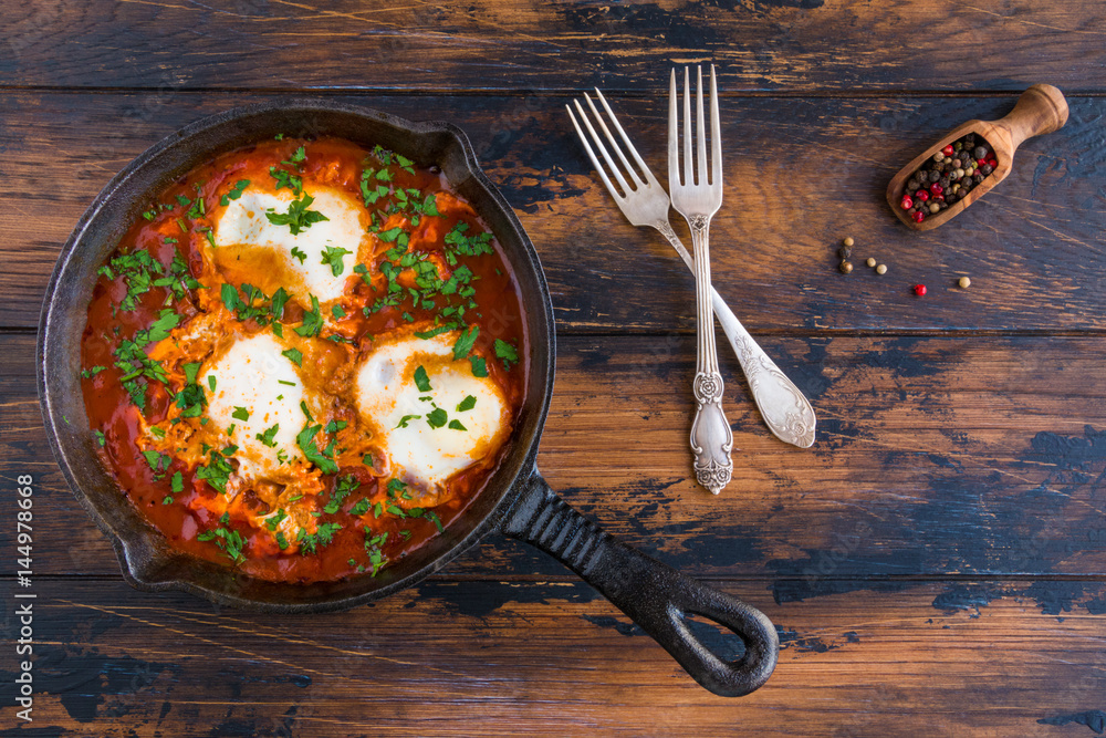 Traditional Arabic dish shakshuka in a black cast iron pan, vintage