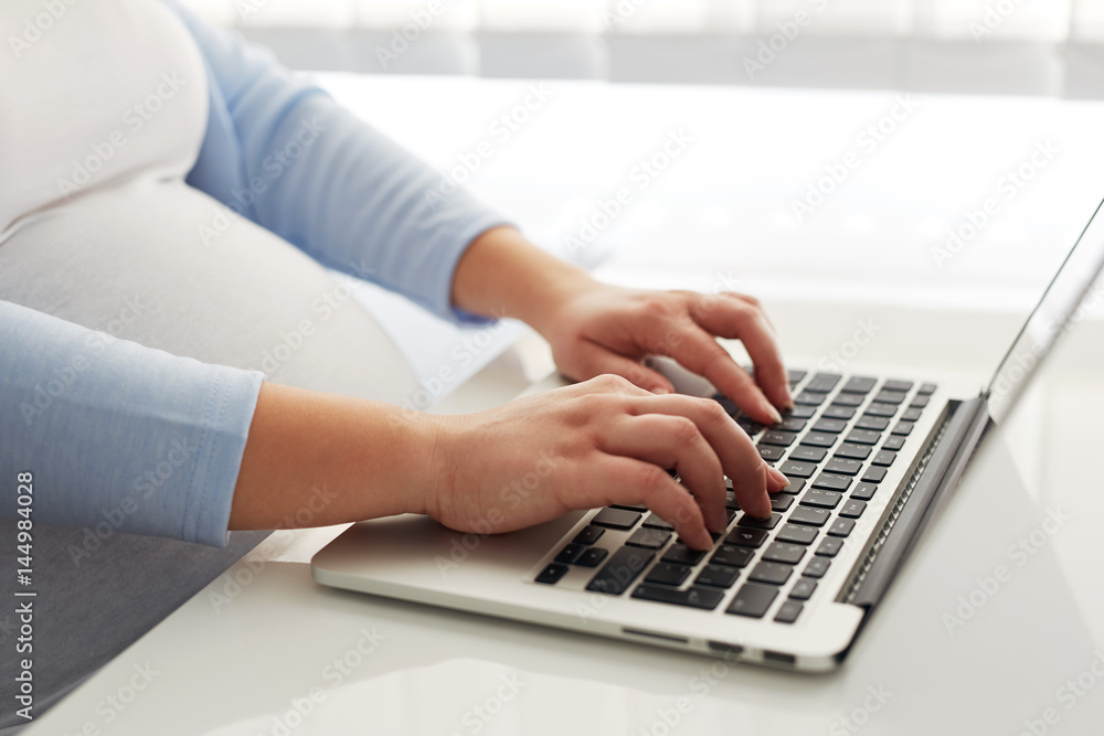 Close up of pregnant woman working on laptop at home Close up of pregnant woman working on laptop at home