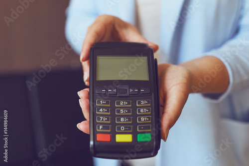 Close up of woman's hands holding payment terminal, toned