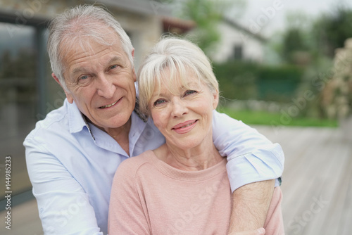 Senior couple embracing in front of new modern house