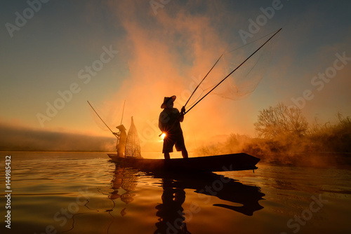 The silluate fisherman boat in river on during sunrise,Thailand
