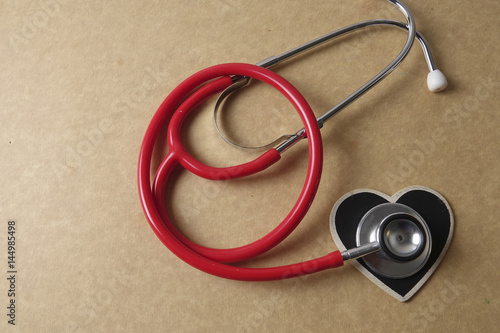 Red stethescope on wooden background. Medical and health care concept.