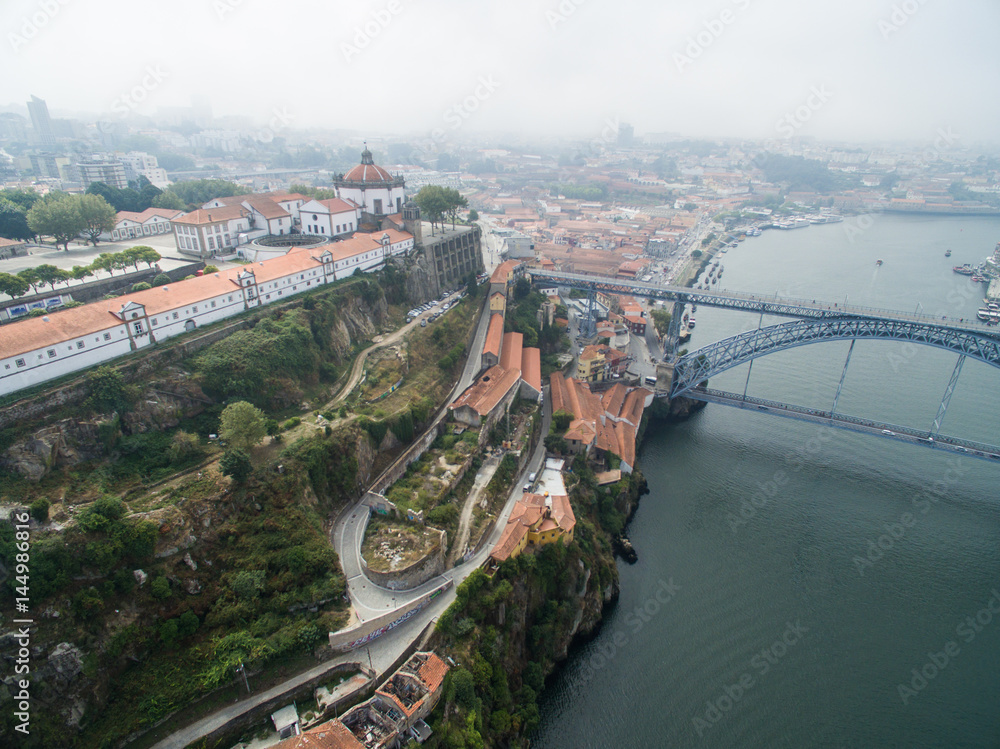 Naklejka premium Panoramic view of the old city of Porto. One flew over the roofs of the houses, a river and a bridge.