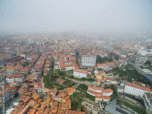 Flight over the narrow streets of the old town of Porto at the fog