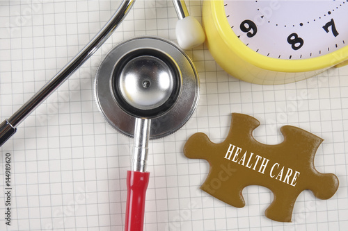 Medical concept with stethoscope,piece of puzzle and coins with HEALTH CARE conceptual text. photo