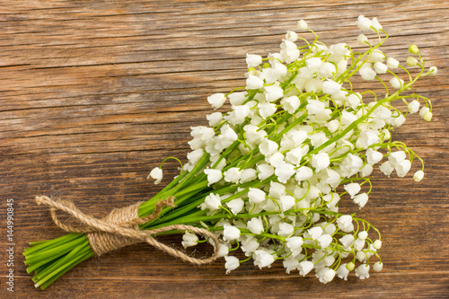 Vintage bouquet of wild flowers, the white scented lilies of the valley on an old wooden plank closeup