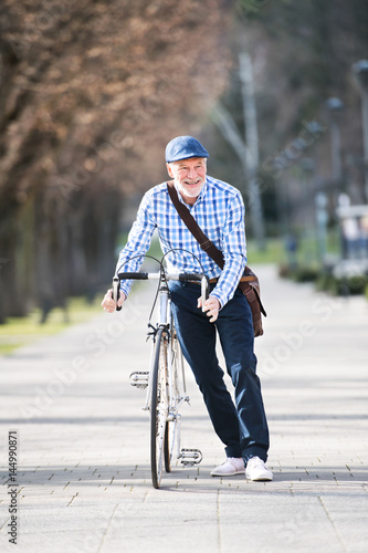 Senior man in blue checked shirt with bicycle in town.