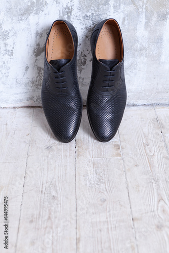 Black men's shoes against a wall in a retro interior in shades of gray.