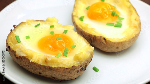 Twice baked potatoes with egg on top on white plate