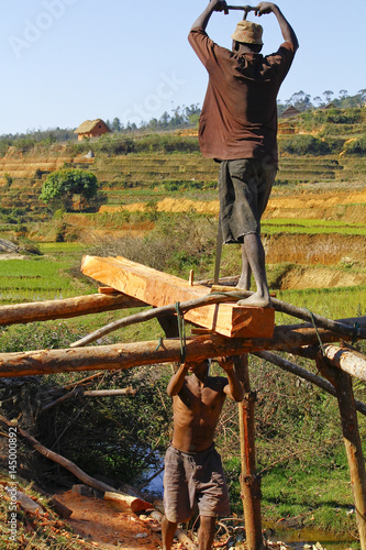 Poor malagasy men cutting timber in makeshift sawmill