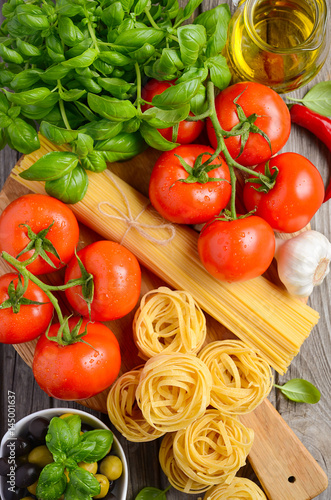 Pasta, vegetables, herbs and spices for Italian food on wooden background, selective focus