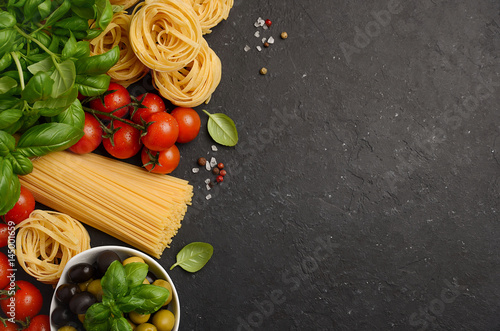 Pasta, vegetables, herbs and spices for Italian food on black background, top view, copy space