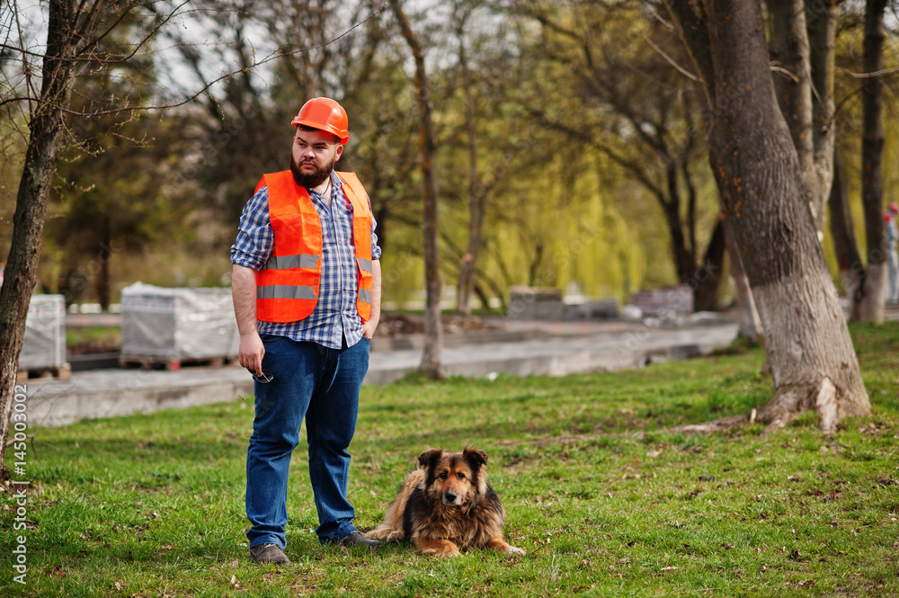 Portrait of brutal beard worker man suit construction worker in safety orange helmet with watchdog. Portrait of brutal beard worker man suit construction worker in safety orange helmet with watchdog.