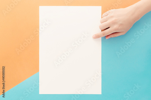 Stationary mock up on blue and orange background. Vertical blank with hand
