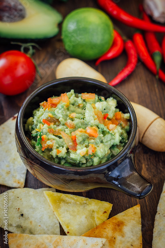 Guacamole with corn chips - nachos, made from avocado, tomatoes and lime.