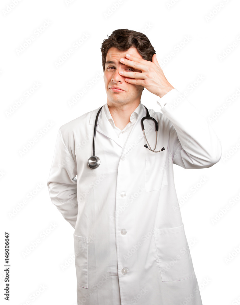 Tired doctor covering his eyes against white background Tired doctor covering his eyes against white background