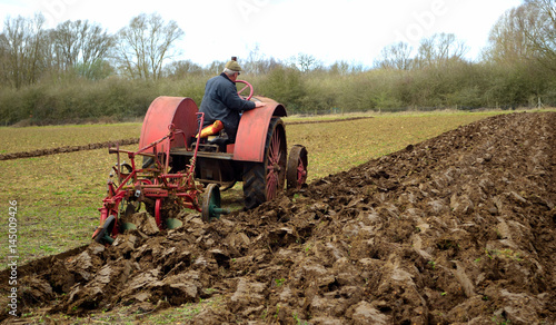  Vintage red International 1930's  tractor ploughing field. 
