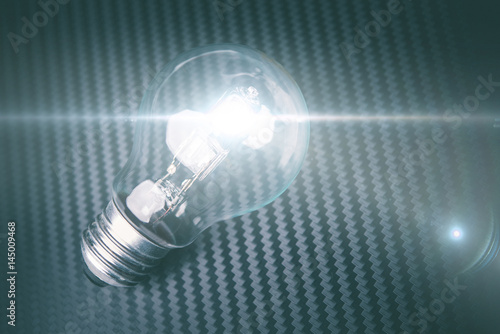 Self illuminating bulb on carbon background. Technology idea concept.