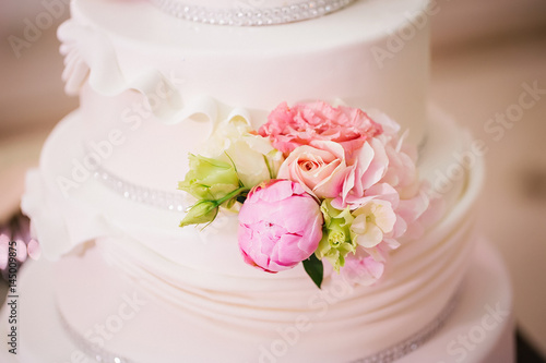 multi-tiered wedding cake decorated with roses and peonies