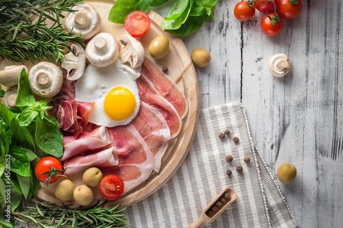 Healthy Mediterranean breakfast ingredients, ham, fried eggs, tomatoes