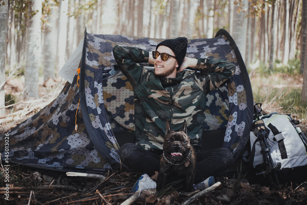Φωτογραφία Man backpacker in the mountain with his camping tent and his French bulldog dog