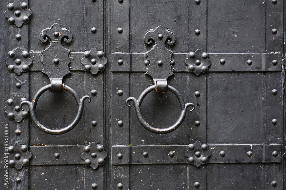 Metal rusty round handle on black wooden door.