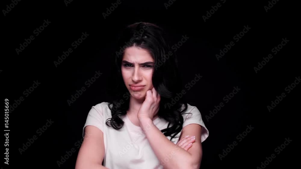 Unhappy displeased young brunette woman is about to cry while standing with arms folded isolated over black Unhappy displeased young brunette woman is about to cry while standing with arms folded isolated over black